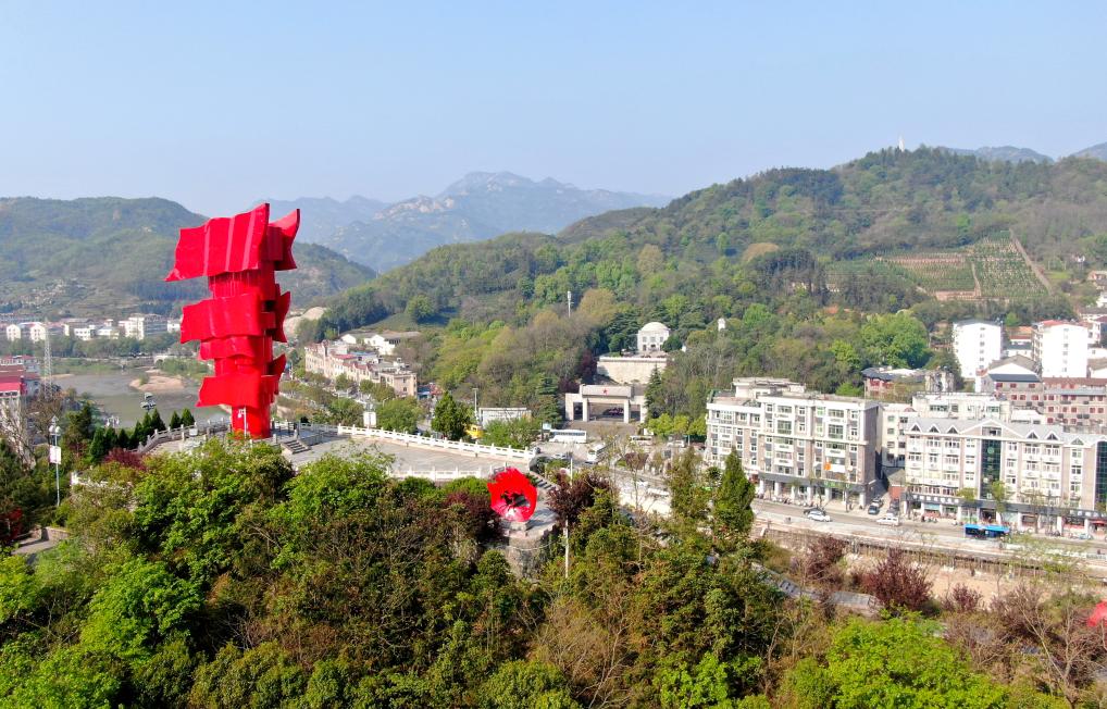 这是2021年4月9日拍摄的鄂豫皖苏区首府革命博物馆附近的英雄山上的“红旗飘飘”主题雕塑(无人机照片)。新华社发